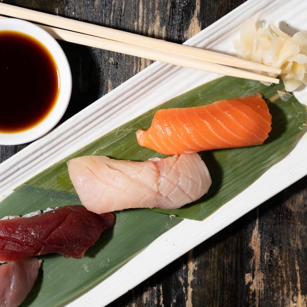 Assorted nigiri sushi, including salmon, tuna, and white fish, with soy sauce, ginger, and wasabi.
